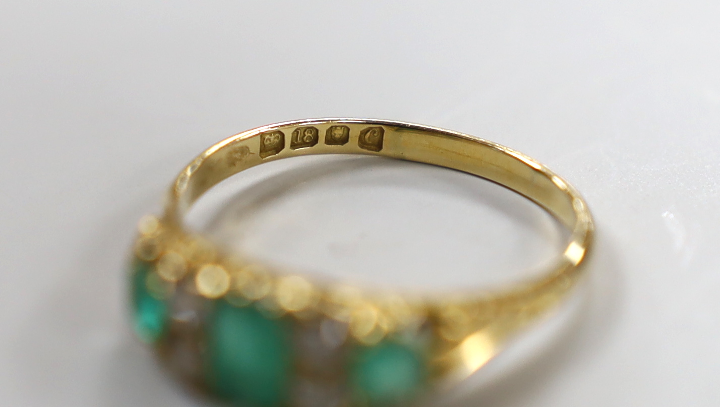 A late Victorian 18ct gold, three stone emerald and four stone diamond spacer set half hoop ring, size P/Q, gross weight 3.5 grams.